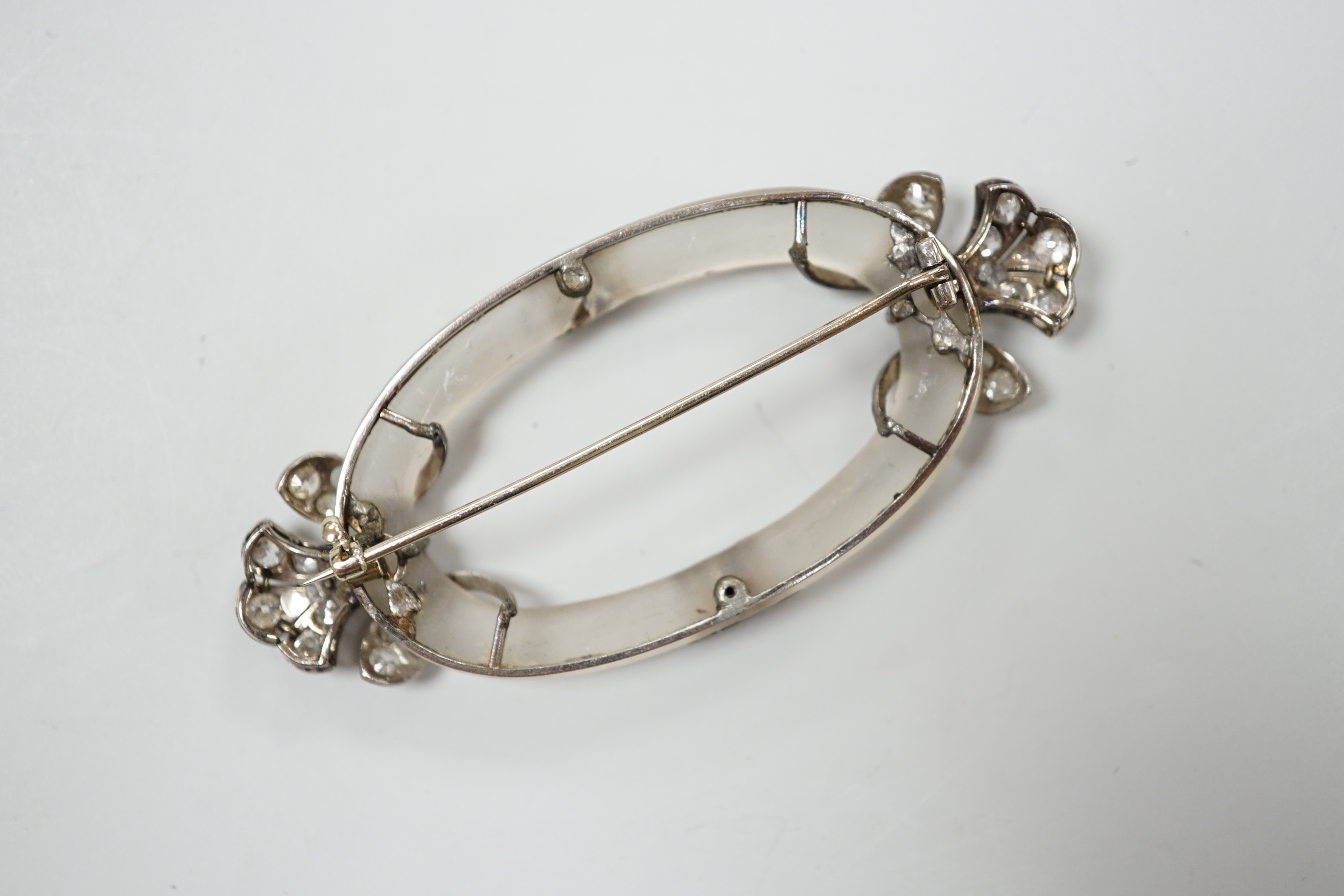 A Belle Epoque diamond set platinum and frosted brooch of open oval form with stylised foliate terminals, width 7cm